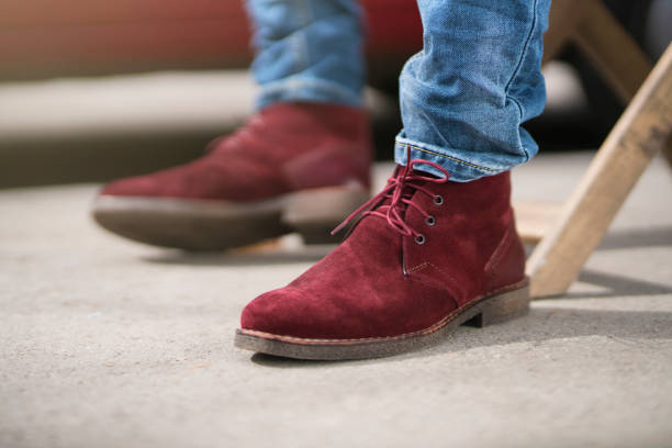 Person wearing red suede shoes with jeans, highlighting footwear for cleaning tips.