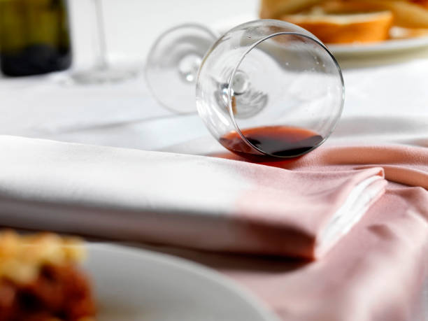 Spilled red wine on a tablecloth with a toppled glass, illustrating a common stain problem.